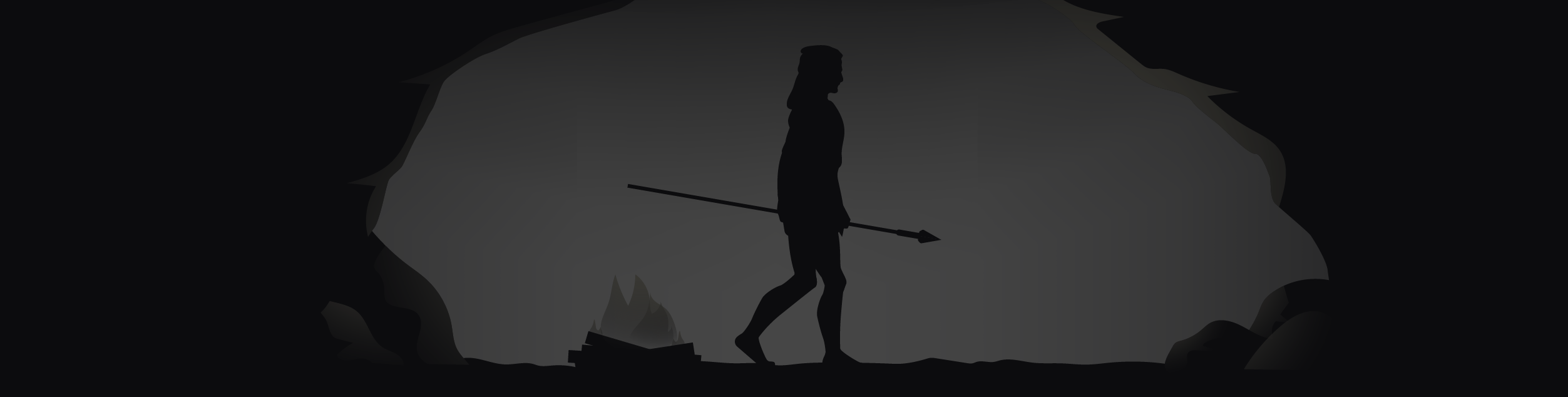 A figure walking through a cave mouth carrying a spear.